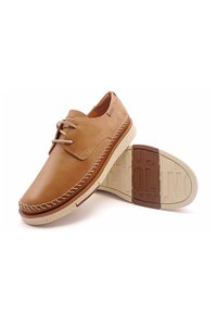 Chaussures en cuir marron à profil bas, avec des coutures contrastées, des lacets ronds et une semelle en caoutchouc crème texturée avec des détails de logo.