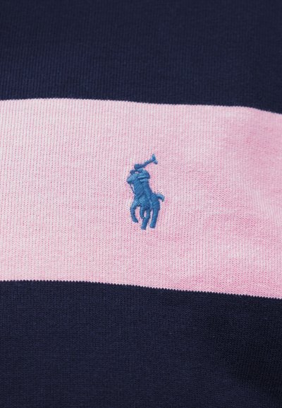 Blå brodert polospiller på hest, sentrert på en horisontal rosa stripe mellom to marineblå striper på strikket stoff.