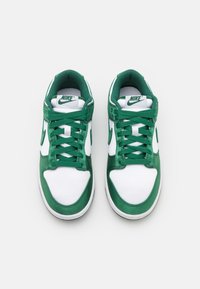 Vysoké tenisky Nike s bílou textilií a zelenými koženými akcenty. Mezi prvky patří zelené tkaničky, gumové podrážky a strukturovaný jazyk.