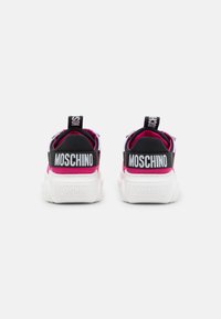 Mustat ja vaaleanpunaiset sneakerit, joissa on verkkokangas yläosa, valkoinen kumipohja ja voimakas "MOSCHINO" -brändäys takana ja kantapäälenkeissä.