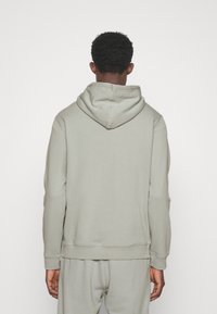 Felpa con cappuccio grigia chiara, caratterizzata da una vestibilità comoda, tessuto morbido e polsini a costine. Design semplice senza loghi o motivi visibili.
