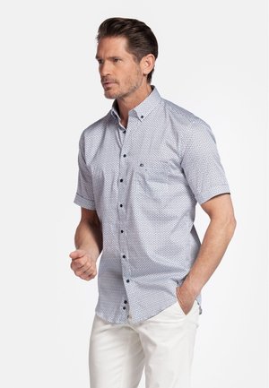 Korte mouw knoopshirt in het wit met een blauw geometrisch patroon. Heeft een kraag, een borstzak en zwarte knopen.