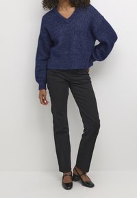 Navy knitted sweater with a V-neck and loose sleeves, paired with fitted black pants and black heeled shoes.