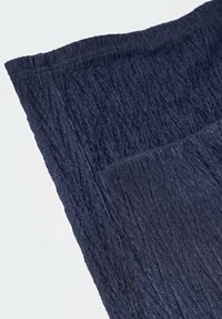 Tissu texturé bleu marine avec un design froissé, montrant des nuances variées et un éclat subtil ; adapté pour des applications vestimentaires ou de décoration intérieure.