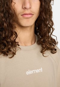 Beige tričko s krátkým rukávem s bílým logem "element". Měkká, hladká textilie s kulatým výstřihem a viditelnými švy.