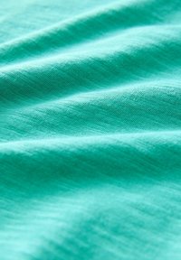 Turquoise stof met een gladde textuur, met subtiele kreukels en een uniforme kleur. Het materiaal lijkt lichtgewicht en zacht te zijn.