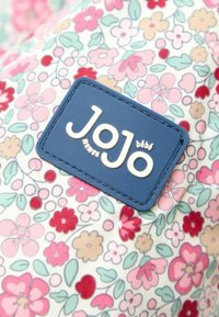 Eticheta Blue JoJo pentru bebe pe material cu un model floral mic, multicolor, în nuanțe de roz, roșu, bej și frunze verzi.