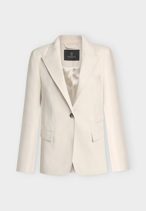 Μπεζ σακάκι με μία κουμπότρυπα, γιακά με σχισμή, τσέπες με καπάκι και εσωτερική φόδρα από σατέν.