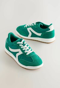 Des chaussures de sport vertes en suède et en maille, avec des accents blancs, un design à lacets, des semelles en caoutchouc et une construction à profil bas.