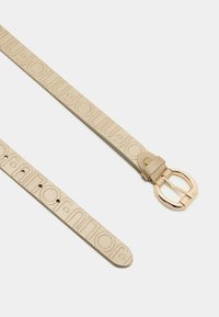 Beżowy skórzany pasek z wytłoczonym wzorem logo, wyposażony w okrągłą złotą klamrę. Teksturowana powierzchnia i regulowane otwory na zapięcie.