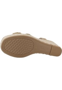 Suela de esparto tejido en color beige con una base de goma estampada. Presenta una superficie texturizada con un ligero tacón y un detalle de marca.