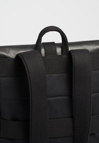 Schwarzer Rucksack mit rechteckiger Form, strapazierfähigem Stoff, verstellbaren Trägern und einem oberen Griff. Glatte Textur mit gebänderten Akzenten.