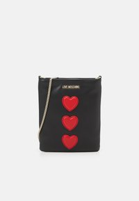 Schwarze Lederhandtasche mit drei roten Herz-Applikationen, goldfarbener Metallkettenschulterriemen und "LOVE MOSCHINO"-Logo in Gold auf der Vorderseite.