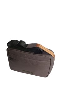 Braune Stoff-Umhängetasche mit schlanker rechteckiger Form, verstellbarem schwarzen Tragegurt und braunem Akzentgurt. Verfügt über eine Reißverschlusstasche und ein Logo-Patch.