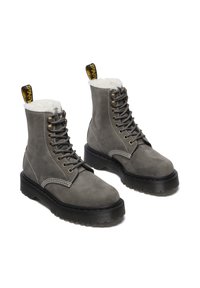 Stivali alla caviglia in suede grigio con rivestimento in finta pelliccia bianca, suola in gomma nera e lacci grigi. Presentano occhielli in metallo e un manico giallo.