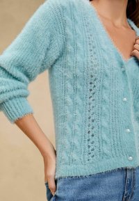 Světle modrý mohérový cardigan má výstřih do V, pletený design s kabelovým vzorem a perlové knoflíky, s žebrovanými manžetami a lemem. Měkká, chlupatá textura.