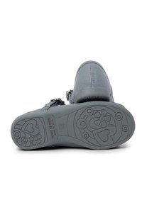 Gray canvas shoe with a textured sole featuring floral and heart patterns. Adjustable strap with metallic hardware for a secure fit.