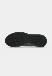 Semelle de chaussure noire avec motif texturé conçu pour la traction sur diverses surfaces.