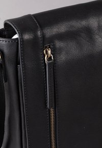 Black leather handbag featuring a smooth texture, gold-tone zipper accent, and contrasting stitching detail along the seams.