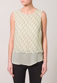 Top senza maniche in tonalità pastello con motivi geometrici in verde, beige e nero; design a strati con una sezione inferiore trasparente; scollatura tonda.