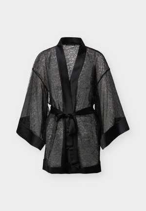 Mustast pitsist hommikumantel satiini ääristusega, laiade varrukate ja satiinvööga, mis on vöökohal seotud, valgel taustal eksponeeritud.