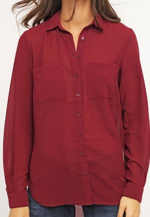 Burgundy button-up shirt with a collar, two chest pockets, long sleeves, and a lightweight, semi-transparent fabric.