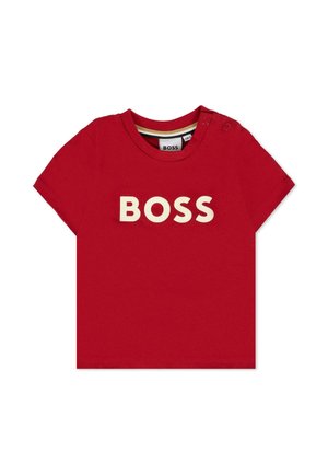 T-shirt rossa in cotone con maniche corte, caratterizzata dalla scritta "BOSS" in grandi lettere color crema sulla parte anteriore. Dettaglio con bottone a pressione sulla spalla.