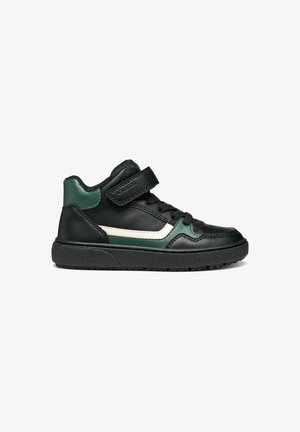 Zapatilla alta negra con acentos verdes y blancos, hecha de cuero, que presenta una correa de Velcro y una suela de goma texturizada.