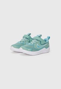 Baskets de sport turquoise clair avec tige en mesh, semelle extérieure blanche, sangle réglable et lacets. Logo Nike emblématique dans une teinte contrastante.