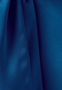 Tissu bleu avec plis visibles et texture, éclairé uniformément pour mettre en valeur la surface lisse et les ombres subtiles.