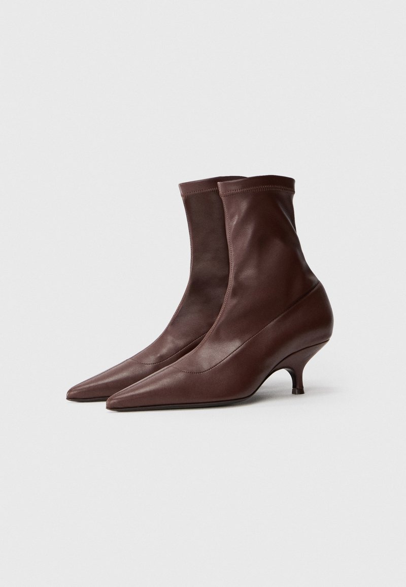 Braune Leder-Stiefeletten mit einem enganliegenden Socken-design, spitzer Zehenpartie und einem geschwungenen Kittenheel, die eine glatte Textur und eine elegante Silhouette aufweisen.