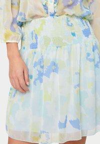 Mekko, jossa on kukkakuosi vaaleansinisissä, vihreissä ja keltaisissa sävyissä. Kevyt kangas, jossa on rypytetty vyötärö ja laaja, laskostettu hame.