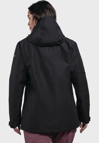 Giacca nera impermeabile con cappuccio, texture liscia e polsini regolabili, caratterizzata da un design semplice e accenti minimalisti.