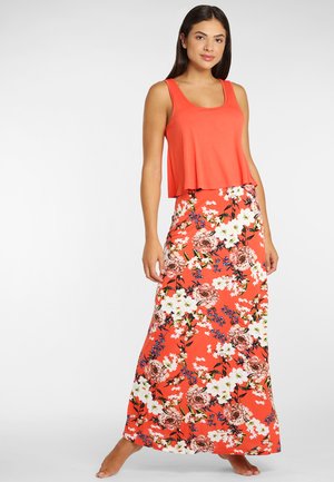 Korallenfarbener Crop-Top mit rundem Ausschnitt, kombiniert mit einem floralem Maxikleid, das große Blüten in Weiß und Rosa auf einem orangefarbenen Hintergrund zeigt.