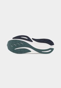 Πάτος αθλητικού παπουτσιού με σκούρο πράσινο και μαύρο υφασμάτινο πέλμα από καουτσούκ σε λευκή βάση πάνω σε απλό ανοιχτό φόντο.