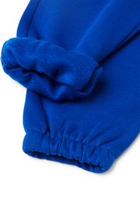 Puño forrado de felpa azul de una prenda, con textura acanalada y cinturilla elástica. Tela suave y vibrante con detalle fruncido.