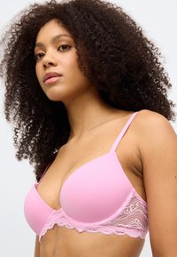 Różowy biustonosz z gładkimi miseczkami i koronkowym wykończeniem. Regulowane ramiączka i delikatny koronkowy akcent u podstawy. Brak wkładek, miękka struktura.
