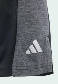 Camiseta deportiva de manga corta en tela gris y negro, con una textura suave y un logo de tres rayas blancas cerca del dobladillo.