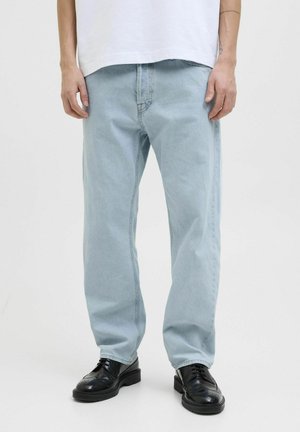 Heledad sinine denim, laheda lõikega, viie taskuga ja sileda tekstuuriga, koos mustade nahkingadega.