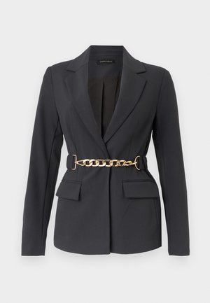 Blazer noir sur mesure avec revers, manches longues, deux poches avant à rabat, et une ceinture décorative en chaîne dorée à la taille.