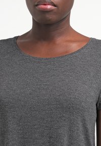 Camiseta de jersey gris con cuello redondo y mangas cortas, que presenta una textura suave y un corte ajustado.