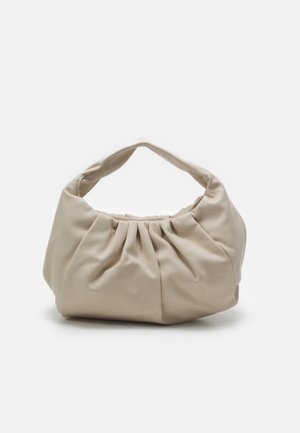 Weiche beiget Lederhandtasche mit gerafften Details und kurzem Henkel, die auf einer weißen Oberfläche liegt.