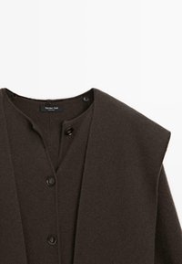 Cardigan en laine marron avec un col profond, une fermeture par boutons et une texture lisse. Confectionné par Massimo Dutti, avec des détails de design minimalistes.