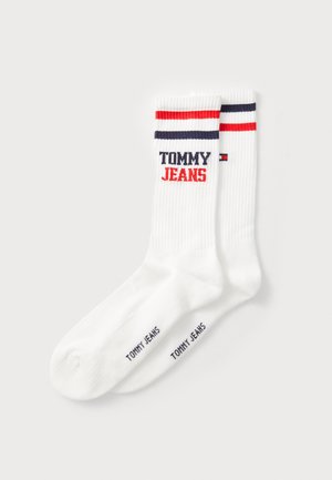 Weiße Baumwollsocken mit horizontalen roten und marineblauen Streifen am Bündchen. Das "TOMMY JEANS"-Logo ist prominent in Rot und Marineblau aufgedruckt.