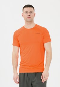 Oranssi lyhythihainen urheilupaita teksturoidusta kankaasta, jossa on pyöreä kaula-aukko ja ommellut saumat. Rinnassa on "ENDURANCE" logo.