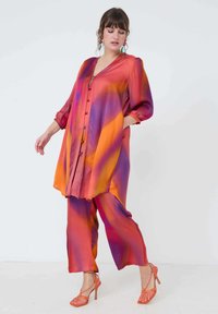Zijden tuniek en wijde broek in een levendige gradient van oranje, roze en paars; beschikt over een knoopsluiting en vloeiende mouwen. Hakhoogte ongeveer 10 cm.