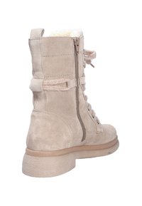 Stivaletto alla caviglia in suede beige con una finitura testurizzata, lacci frontali, zip laterale e foderato in pelliccia sintetica. Presenta una suola spessa e testurizzata.