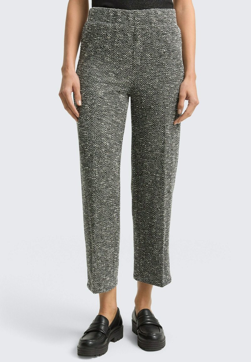 Grijze broek met visgraatmotief, een ontspannen pasvorm, elastische tailleband en rechte pijpen, gecombineerd met zwarte loafers met plateauzolen.