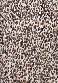 Leopardo rašto pinti audinys su baltu pagrindu ir juodais bei smėliniais taškeliais, sukuriantis tekstūrinį ir dinamišką raštą.