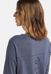 Heathergraues Langarmshirt mit lockerer Passform, ausgestattet mit einem dezenten Logo-Druck auf der Rückseite und einem weichen, strukturierten Stoff.